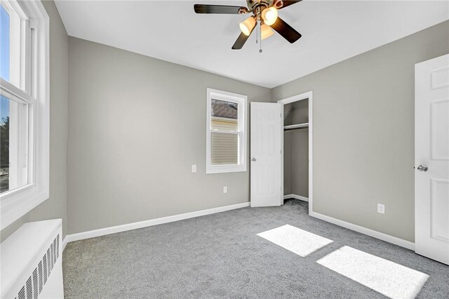 unfurnished bedroom featuring a closet, ceiling fan, radiator heating unit, and carpet