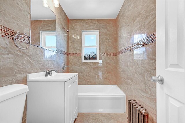 full bathroom featuring radiator heating unit, vanity, tile walls, and toilet