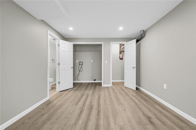 unfurnished bedroom with ensuite bath and light hardwood / wood-style flooring