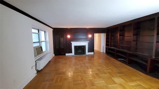 unfurnished living room featuring cooling unit, radiator, light parquet flooring, and ornamental molding