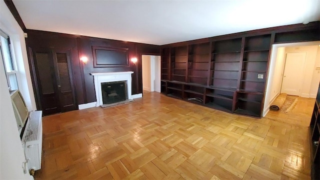 unfurnished living room with built in features and light parquet flooring