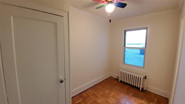 empty room featuring ceiling fan, radiator heating unit, ornamental molding, and parquet flooring