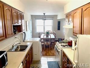 kitchen with sink, hanging light fixtures, ventilation hood, light tile patterned flooring, and appliances with stainless steel finishes