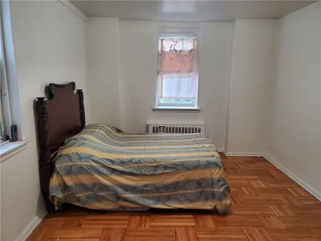 bedroom featuring radiator heating unit and light parquet floors