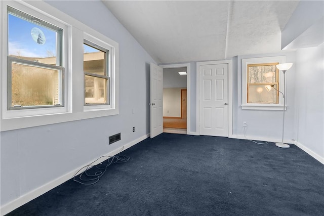 carpeted empty room featuring vaulted ceiling