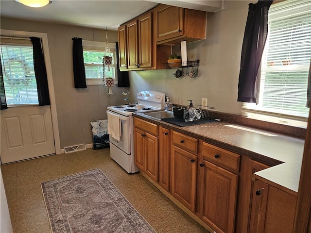 kitchen featuring white range with electric cooktop, sink, and a wealth of natural light