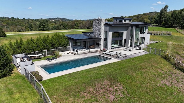 rear view of house featuring an outdoor hangout area, a fenced in pool, a patio area, and a lawn