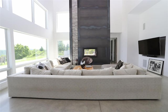 living room with a high ceiling, a large fireplace, and a wealth of natural light