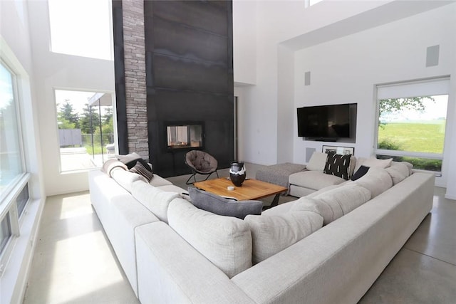 living room featuring a wealth of natural light, a large fireplace, and a high ceiling