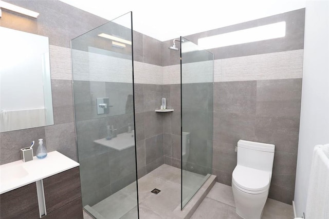 bathroom featuring tiled shower, vanity, toilet, and tile walls