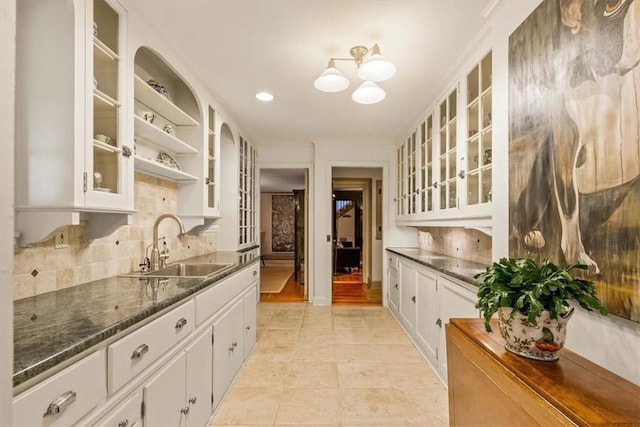 kitchen with white cabinetry, sink, tasteful backsplash, dark stone counters, and light tile patterned floors