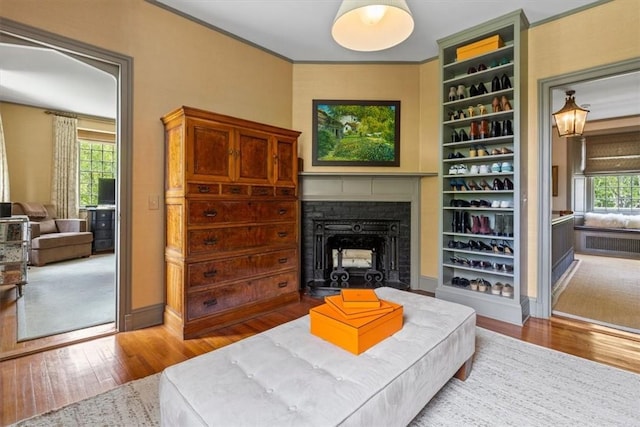 living room featuring built in shelves, wood-type flooring, ornamental molding, and a wealth of natural light