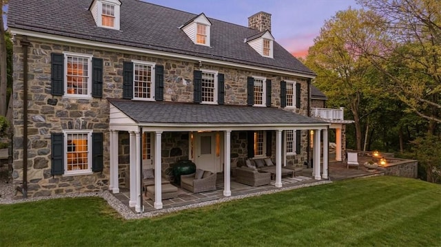 back house at dusk with a yard, an outdoor hangout area, and a patio area