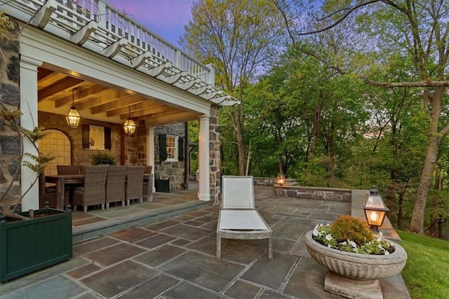 patio terrace at dusk featuring an outdoor stone fireplace