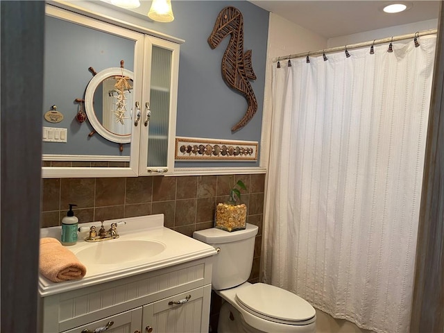 bathroom with vanity, toilet, and tile walls