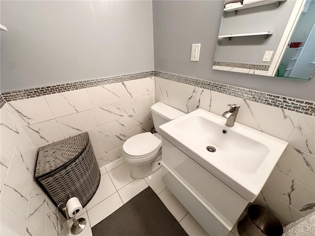 bathroom featuring tile patterned flooring, vanity, toilet, and tile walls