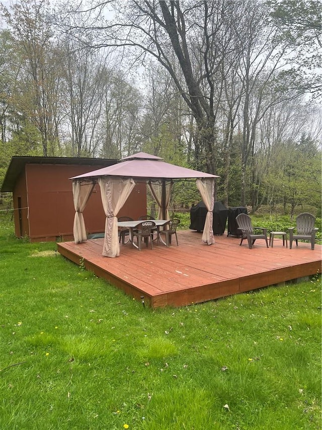 wooden deck featuring a gazebo, a yard, and a fire pit