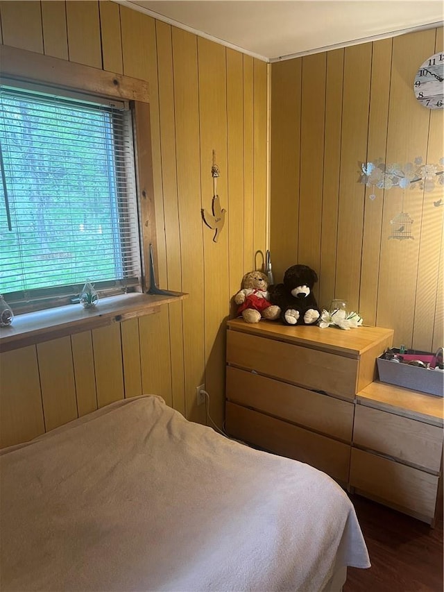 bedroom with dark hardwood / wood-style flooring and wooden walls