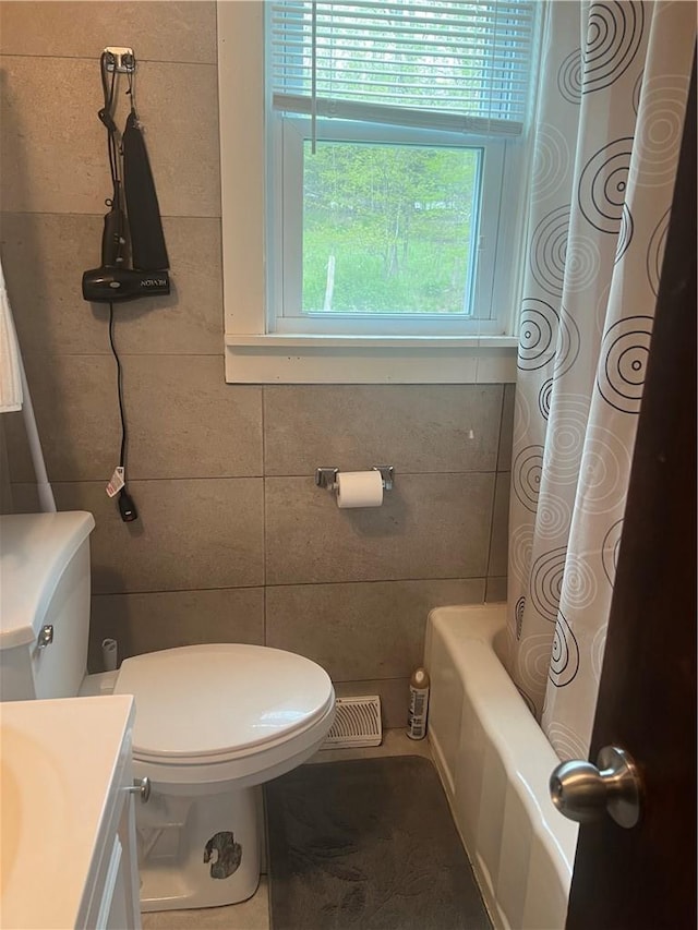 full bathroom with shower / tub combo, vanity, tile walls, and toilet