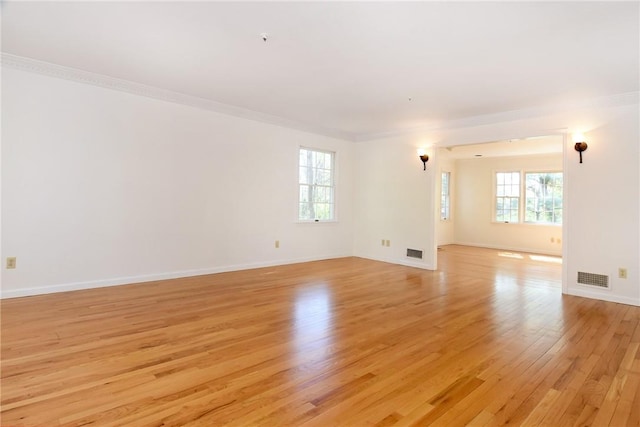 empty room with crown molding and light hardwood / wood-style flooring