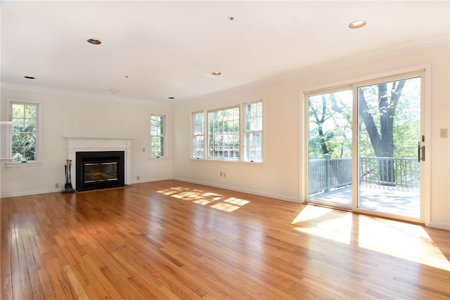 unfurnished living room featuring light hardwood / wood-style floors, plenty of natural light, and crown molding