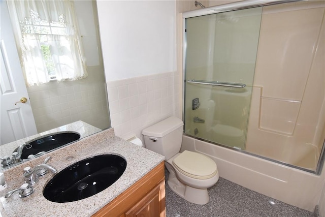 full bathroom featuring vanity, enclosed tub / shower combo, tile walls, and toilet