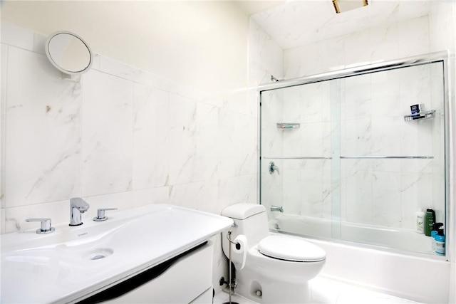 full bathroom with vanity, toilet, shower / bath combination with glass door, and tile walls