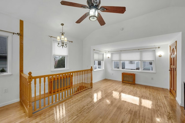 unfurnished living room with ceiling fan with notable chandelier, light hardwood / wood-style flooring, and lofted ceiling