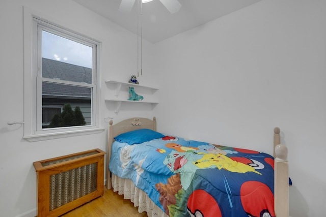 bedroom featuring hardwood / wood-style floors, ceiling fan, and radiator heating unit