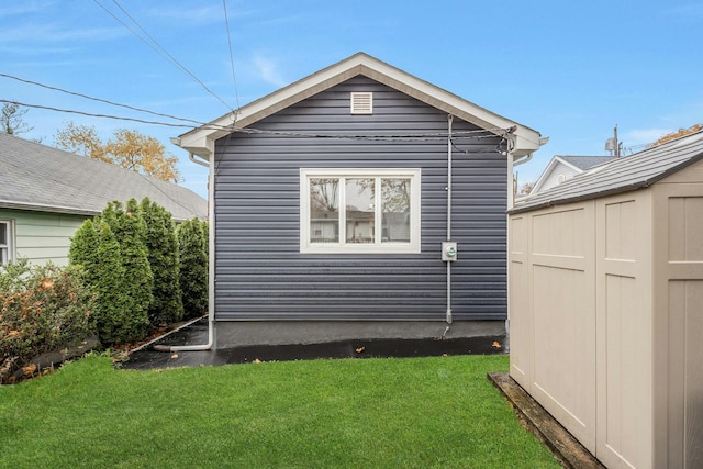 view of side of property with a yard and a shed