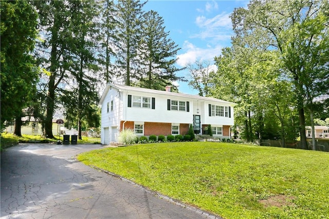 split foyer home featuring a garage and a front yard