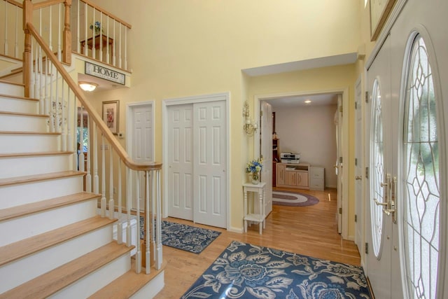 entryway featuring a towering ceiling, healthy amount of natural light, wood finished floors, stairway, and baseboards