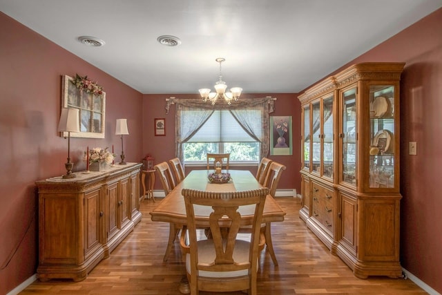 dining room with a chandelier, light wood-style floors, a baseboard heating unit, baseboards, and baseboard heating