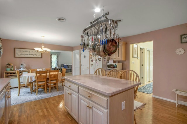 kitchen featuring white appliances, a chandelier, light wood-type flooring, and a breakfast bar area