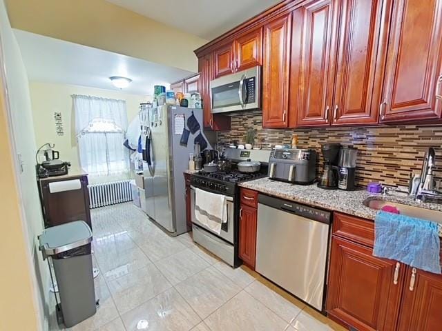 kitchen featuring backsplash, sink, light stone countertops, and stainless steel appliances