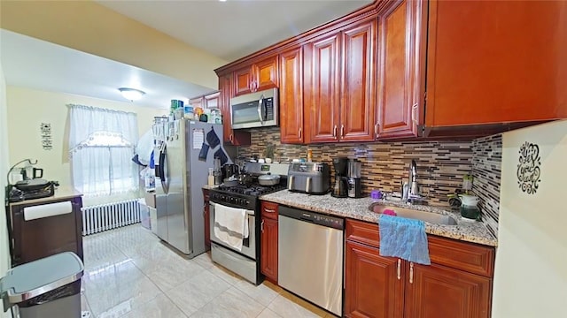 kitchen with appliances with stainless steel finishes, tasteful backsplash, light stone counters, sink, and light tile patterned floors