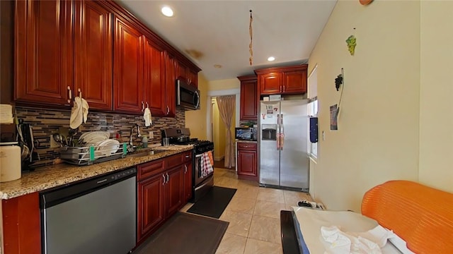 kitchen featuring tasteful backsplash, light stone counters, stainless steel appliances, sink, and light tile patterned floors