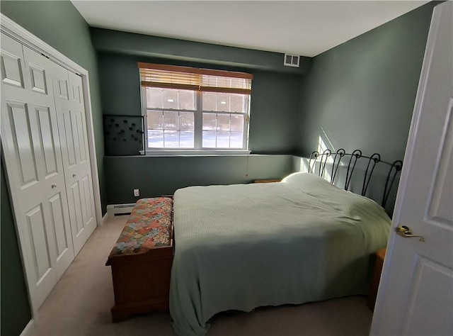 carpeted bedroom featuring baseboard heating and a closet