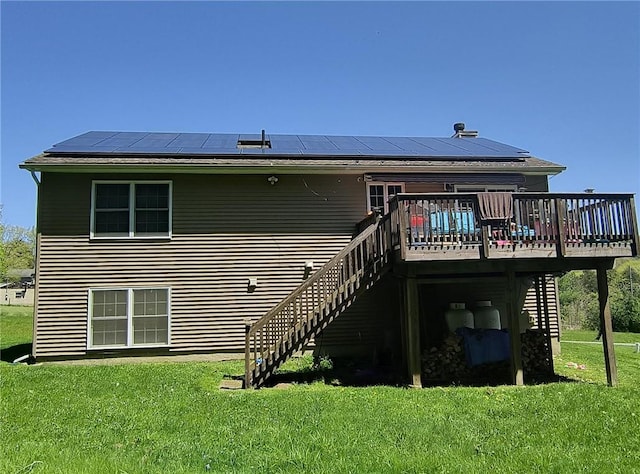 rear view of property featuring a wooden deck, a yard, and solar panels