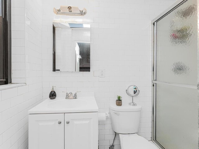 bathroom featuring walk in shower, vanity, toilet, and tile walls