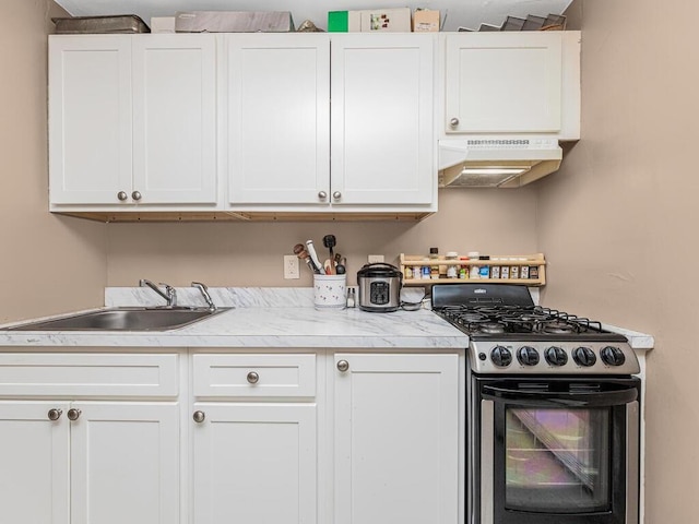 kitchen featuring stainless steel gas stove, white cabinetry, sink, and extractor fan