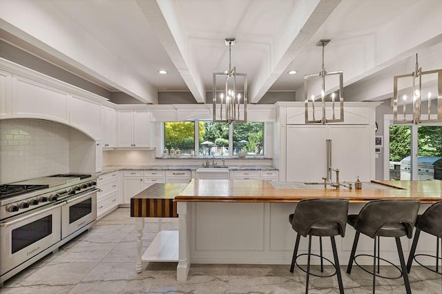 kitchen with beam ceiling, butcher block counters, white cabinetry, a kitchen island, and high end appliances