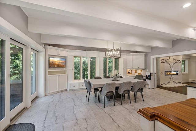 dining space featuring a premium fireplace and beamed ceiling