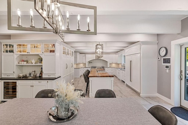 dining area featuring beamed ceiling, beverage cooler, and sink