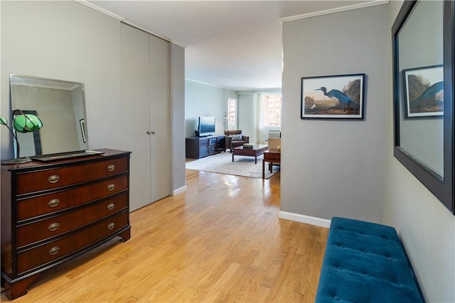 hallway with light wood-type flooring and crown molding