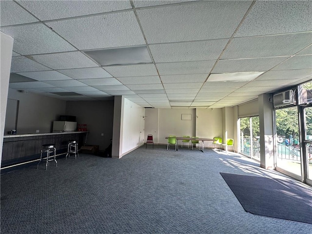 interior space featuring a paneled ceiling and dark colored carpet