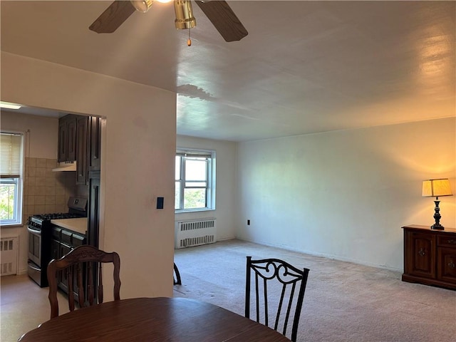 carpeted dining room with radiator and ceiling fan