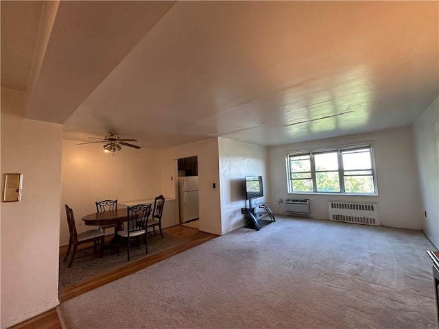 interior space with carpet flooring, ceiling fan, radiator heating unit, and a wall mounted air conditioner