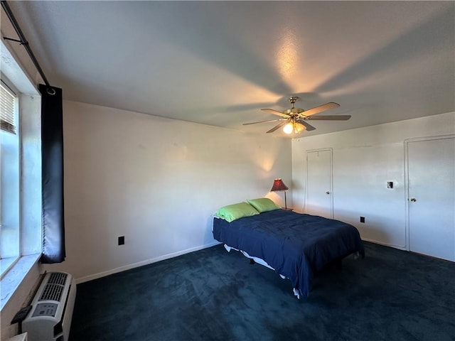 bedroom featuring dark carpet, ceiling fan, and an AC wall unit