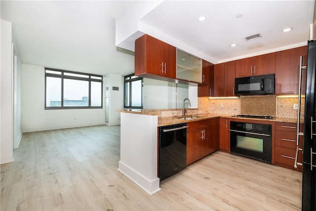 kitchen featuring backsplash, black appliances, sink, light stone countertops, and light hardwood / wood-style floors